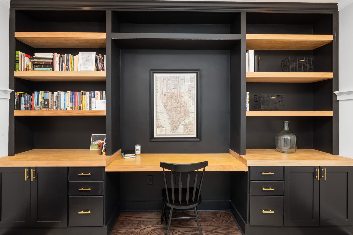 Black built-in desk and shelving wall with a butcher block top